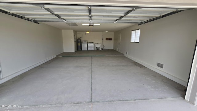 garage featuring independent washer and dryer, a sink, visible vents, electric water heater, and a garage door opener