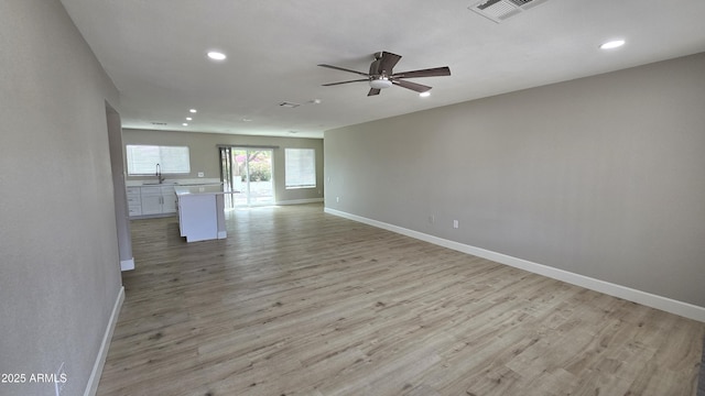 unfurnished living room featuring a sink, visible vents, ceiling fan, baseboards, and recessed lighting