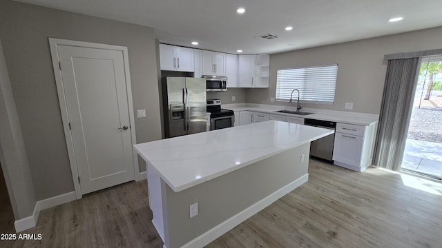 kitchen featuring stainless steel appliances, open shelves, a sink, white cabinetry, and light wood-type flooring
