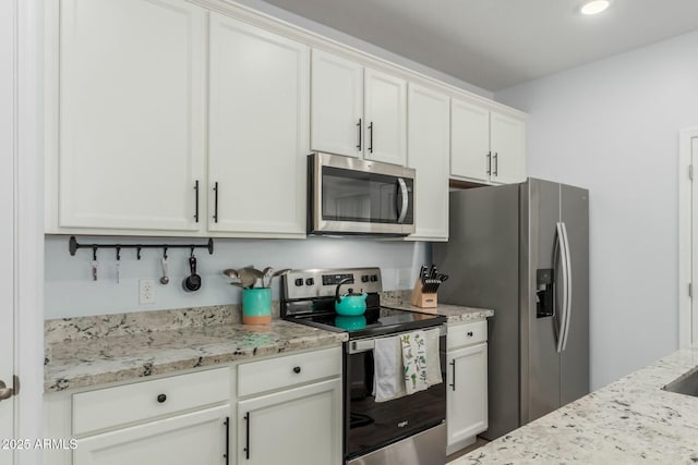 kitchen with light stone counters, stainless steel appliances, and white cabinets