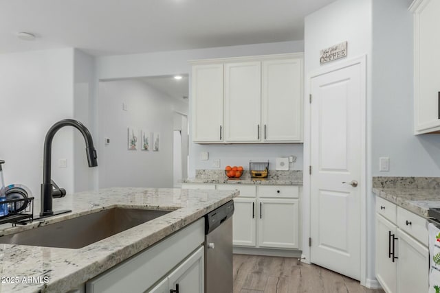 kitchen with sink, white cabinets, stainless steel dishwasher, light stone counters, and light hardwood / wood-style floors