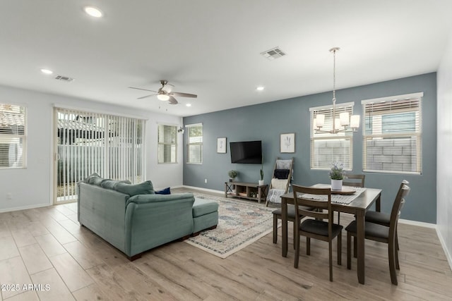 living room featuring ceiling fan with notable chandelier and light wood-type flooring