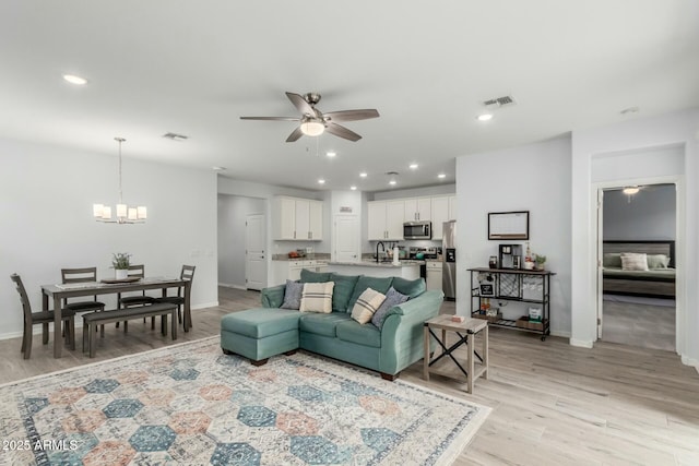 living room featuring sink, ceiling fan with notable chandelier, and light hardwood / wood-style flooring