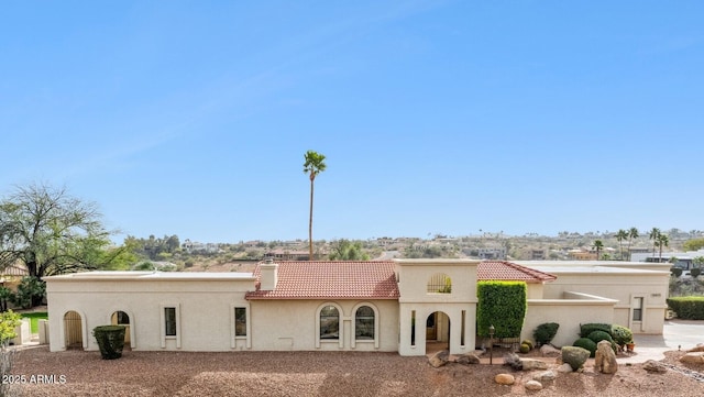 view of front of property with a chimney, a tiled roof, and stucco siding