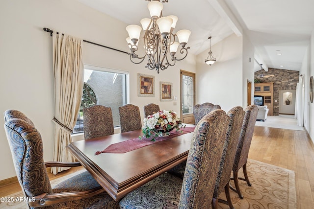 dining area featuring vaulted ceiling with beams, light wood-style flooring, and a notable chandelier