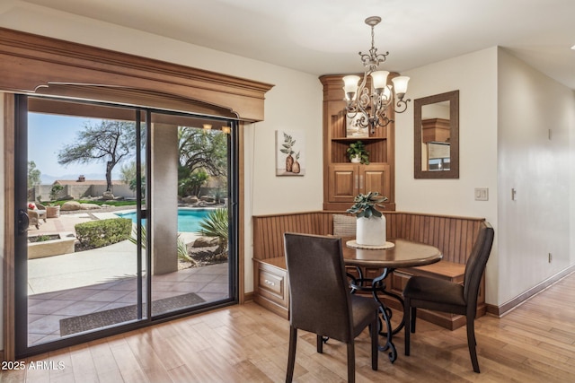 dining room with a chandelier, baseboards, and light wood-style floors