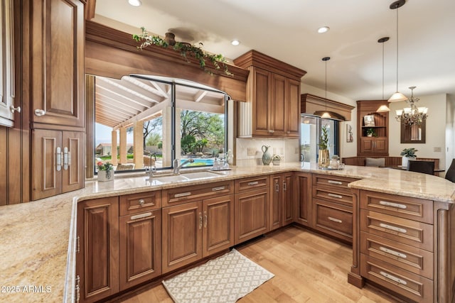 kitchen with a peninsula, light wood-style floors, backsplash, and a sink