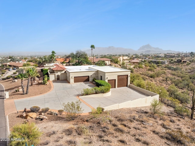 southwest-style home featuring concrete driveway, a mountain view, an attached garage, and stucco siding