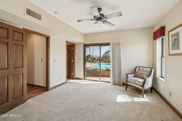 living area with light carpet, baseboards, visible vents, and a ceiling fan