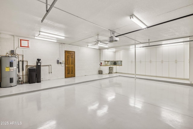 garage featuring a garage door opener, concrete block wall, water heater, and a ceiling fan