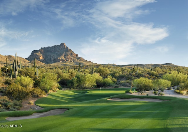 view of community featuring a yard, view of golf course, and a mountain view