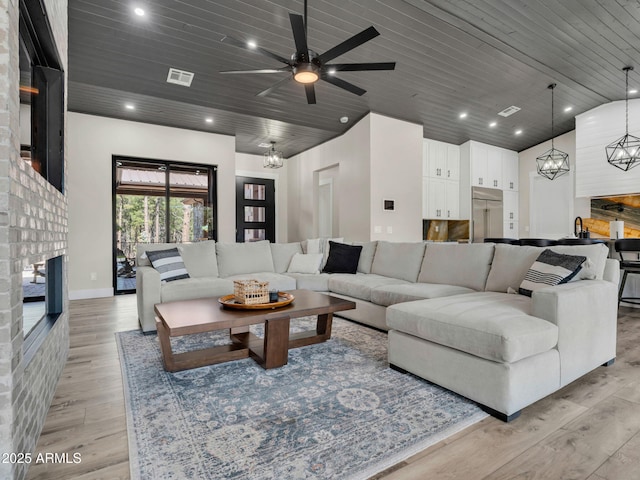 1137 Timbernook Xing, Williams, AZ 86046 - living room with a fireplace, a chandelier, wooden ceiling, ceiling fan, and light wood-style flooring