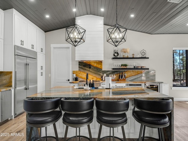 1137 Timbernook Xing, Williams, AZ 86046 - kitchen featuring built in fridge, wood ceiling, lofted ceiling, light stone counters, and light wood finished floors