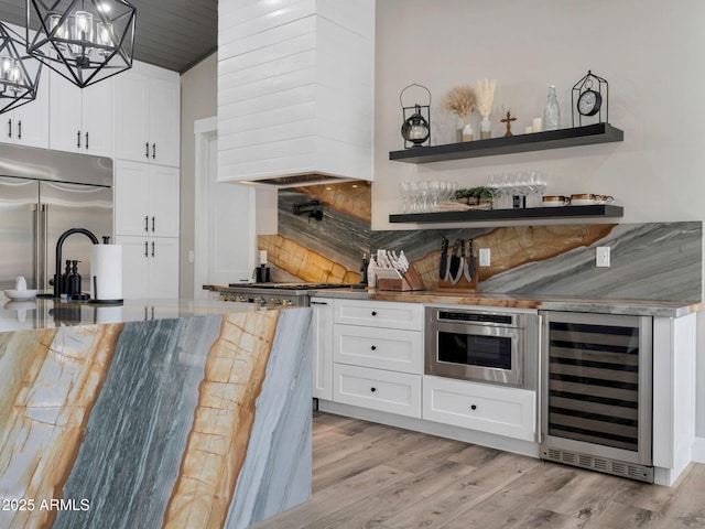1137 Timbernook Xing, Williams, AZ 86046 - indoor dry bar with wine cooler, stainless steel built in fridge, custom exhaust hood, light wood-style flooring, and a chandelier