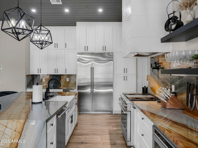 1137 Timbernook Xing, Williams, AZ 86046 - kitchen with premium appliances, a chandelier, light wood-style flooring, tasteful backsplash, and light stone counters