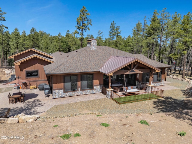 1137 Timbernook Xing, Williams, AZ 86046 - rear view of house with stone siding, a patio, roof with shingles, a chimney, and board and batten siding