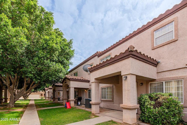 125 S 56th St Unit 124, Mesa, AZ 85206 - rear view of property featuring stucco siding, cooling unit, a lawn, and a tiled roof
