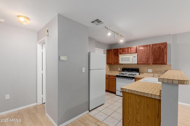 125 S 56th St Unit 124, Mesa, AZ 85206 - kitchen featuring white appliances, a sink, light countertops, decorative backsplash, and a peninsula