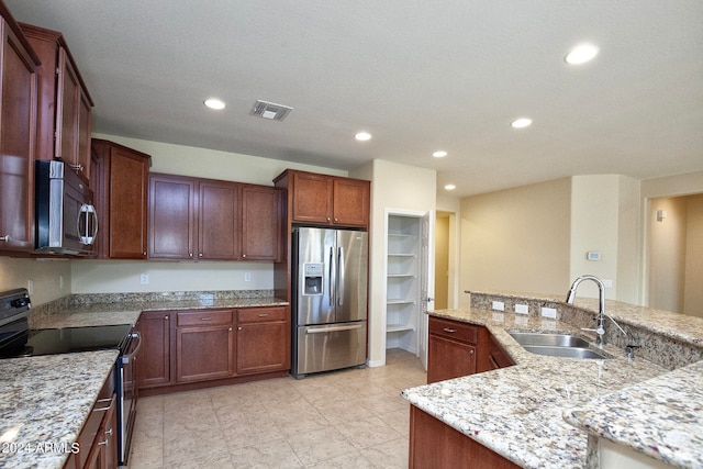 kitchen featuring stainless steel appliances, light tile flooring, a textured ceiling, light stone counters, and sink