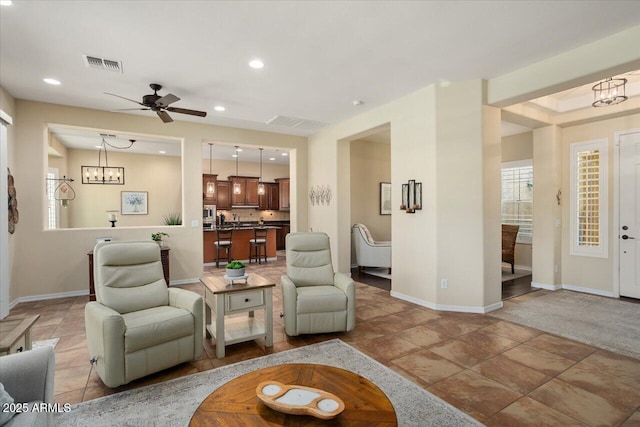 living room with ceiling fan with notable chandelier