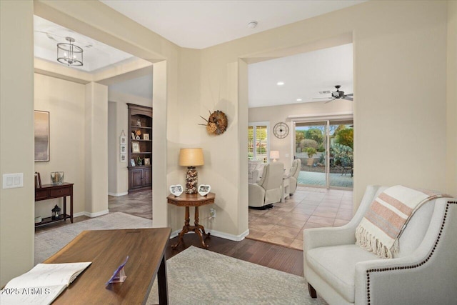 living area featuring wood-type flooring and ceiling fan with notable chandelier