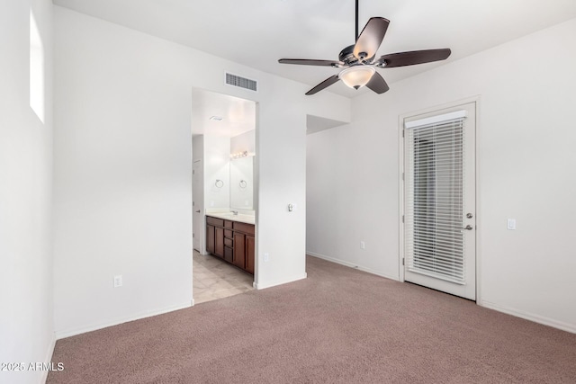 unfurnished bedroom with ceiling fan, light colored carpet, and ensuite bath