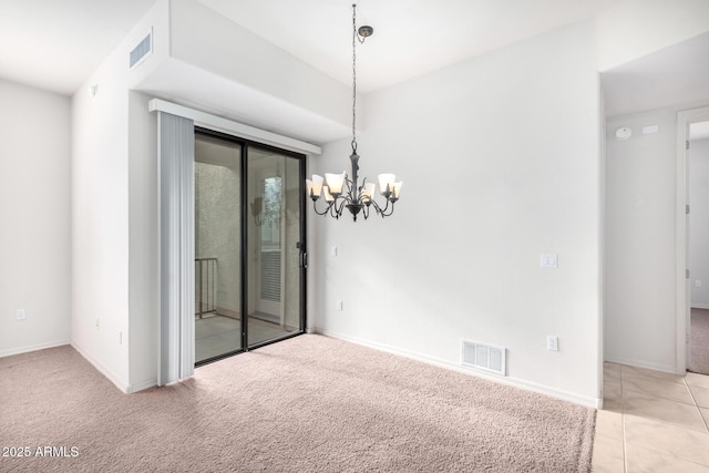 carpeted empty room featuring a notable chandelier