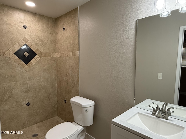 bathroom with vanity, toilet, and a tile shower