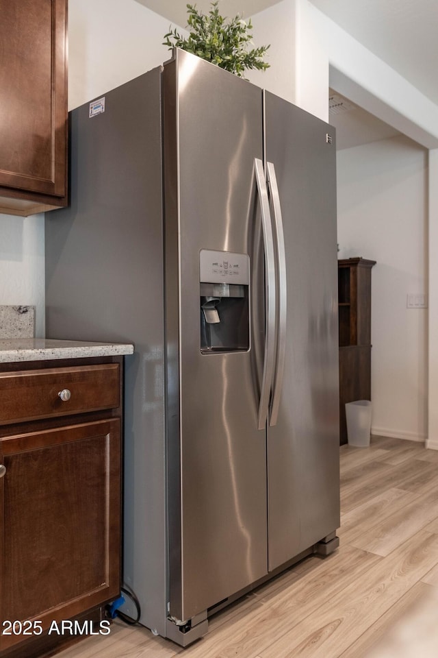 kitchen featuring dark brown cabinets, stainless steel fridge, and light hardwood / wood-style flooring