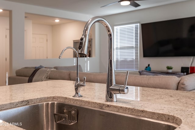 room details with light stone counters, sink, and ceiling fan