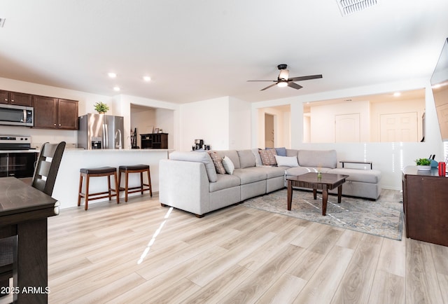 living room featuring ceiling fan and light hardwood / wood-style floors