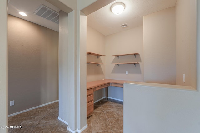 unfurnished office featuring tile patterned flooring and built in desk