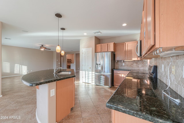 kitchen featuring appliances with stainless steel finishes, tasteful backsplash, sink, decorative light fixtures, and a center island with sink