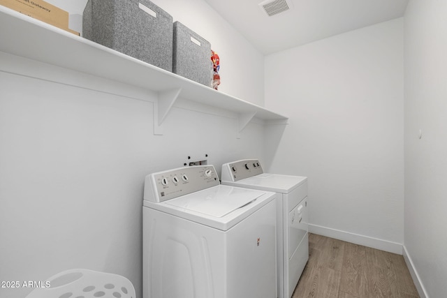 clothes washing area with separate washer and dryer and light wood-type flooring