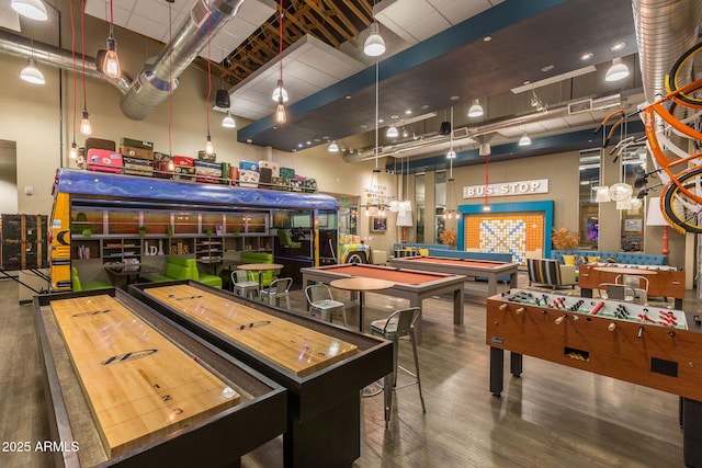 recreation room featuring hardwood / wood-style floors and a towering ceiling