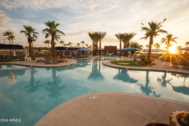 pool at dusk featuring a patio area