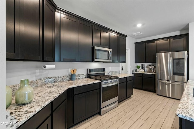 kitchen featuring stainless steel appliances and light stone counters