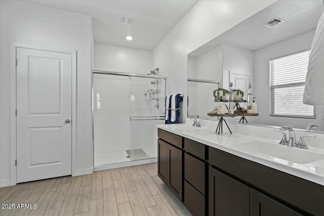 bathroom featuring a shower with door and vanity