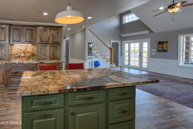 kitchen with crown molding, dark hardwood / wood-style floors, green cabinetry, a kitchen island, and french doors