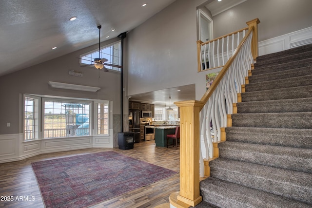 stairway with hardwood / wood-style flooring, ceiling fan, and high vaulted ceiling