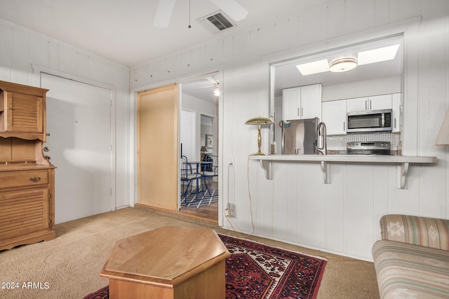 kitchen with ceiling fan, white cabinets, stainless steel appliances, and light carpet