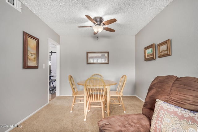 carpeted dining room featuring ceiling fan and a textured ceiling