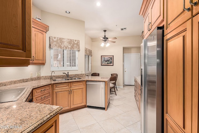 kitchen with light tile patterned flooring, sink, light stone counters, appliances with stainless steel finishes, and ceiling fan