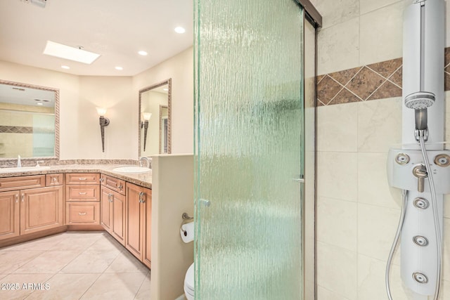 bathroom featuring a skylight, vanity, toilet, a shower with door, and tile patterned floors