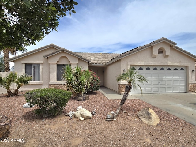 view of front of house with stucco siding, an attached garage, driveway, and a tiled roof
