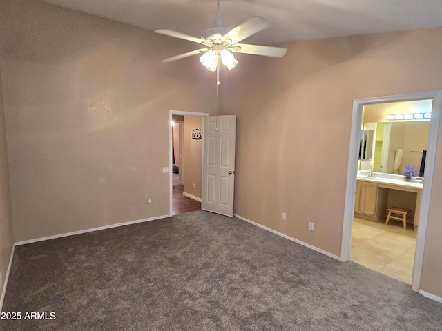 unfurnished bedroom with carpet, baseboards, ensuite bathroom, and a ceiling fan