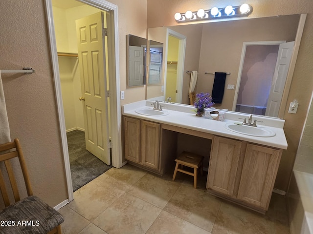 bathroom featuring double vanity, a spacious closet, tile patterned floors, and a textured wall