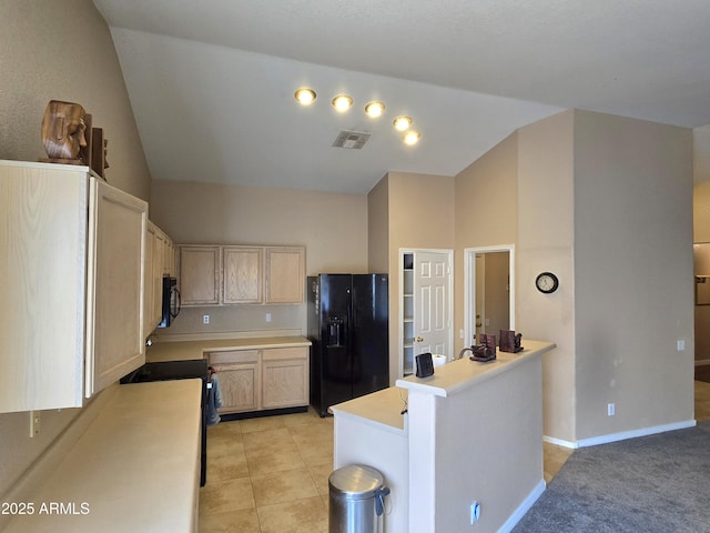kitchen featuring black appliances, light countertops, vaulted ceiling, light brown cabinetry, and baseboards