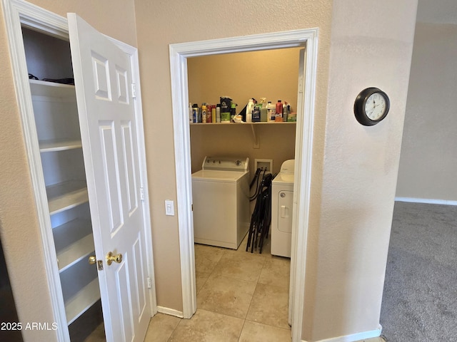 washroom featuring washing machine and clothes dryer, light tile patterned floors, baseboards, and a textured wall