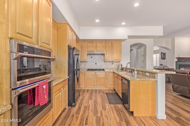 kitchen with appliances with stainless steel finishes, light brown cabinets, hardwood / wood-style flooring, and sink